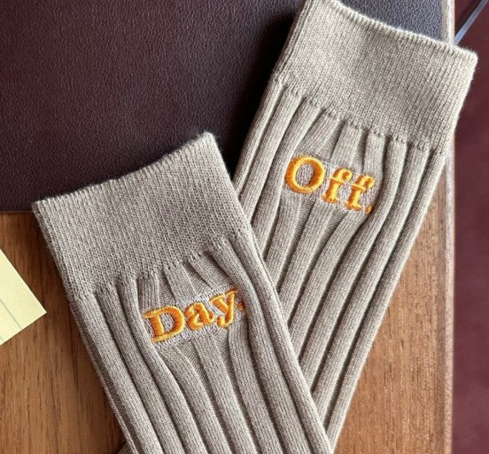 a pair of gray socks with embroidered words on them